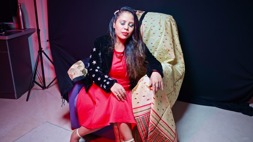 Curly haired singer crafts vocal layers by music studio, Fashionable diva sings softly inside an audio booth, Lady Performer in red outfit croon live at the venue, Melody maker hums wears black jacket
