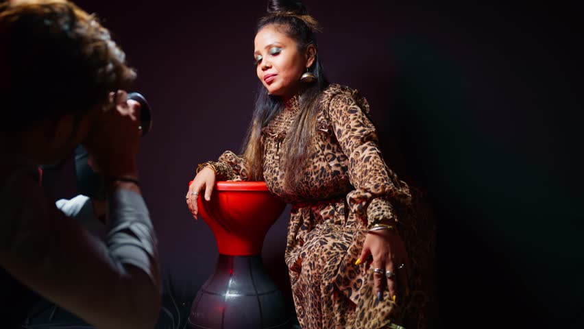 Photographer takes picture of smiling beauty, Elegant woman displays her pose under spotlight, Fashion Model wears bold outfit in studio shoot, Confident girl sits with style for the camera, Portfolio
