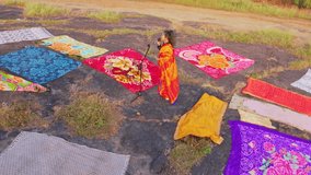 Drone shot sari wear vocalist croon by mic amid vivid cloth, Aerial view singer singing in microphone on rocky land, Music video is captured outside with artist, Female performer near textile, Crooner - Powered by Shutterstock - Get 15% off with code: PIKWIZARD15