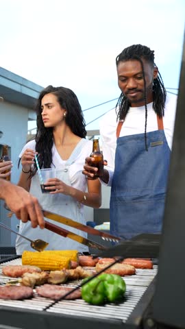 Friends gathering on urban rooftop, grilling diverse meals and sharing laughter while enjoying summer evening drinks against city skyline backdrop