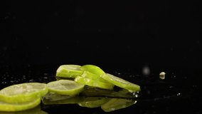 Lime slices fall onto a reflective surface, creating splashes against a dark background with dramatic lighting - Powered by Shutterstock - Get 15% off with code: PIKWIZARD15