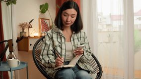 Asian Japanese business woman businesswoman writing notes notebook using mobile phone smartphone write information female at home indoor Chinese Korean girl entrepreneur tasks working online planner - Powered by Shutterstock - Get 15% off with code: PIKWIZARD15