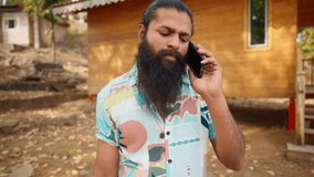Bearded man talk on mobile at peaceful retreat, Rugged traveler speaks leisurely by smartphone outdoor, Day tripper takes call during scenic break, Vacationer in casual attire uses phone, Tourist zone - Powered by Shutterstock - Get 15% off with code: PIKWIZARD15