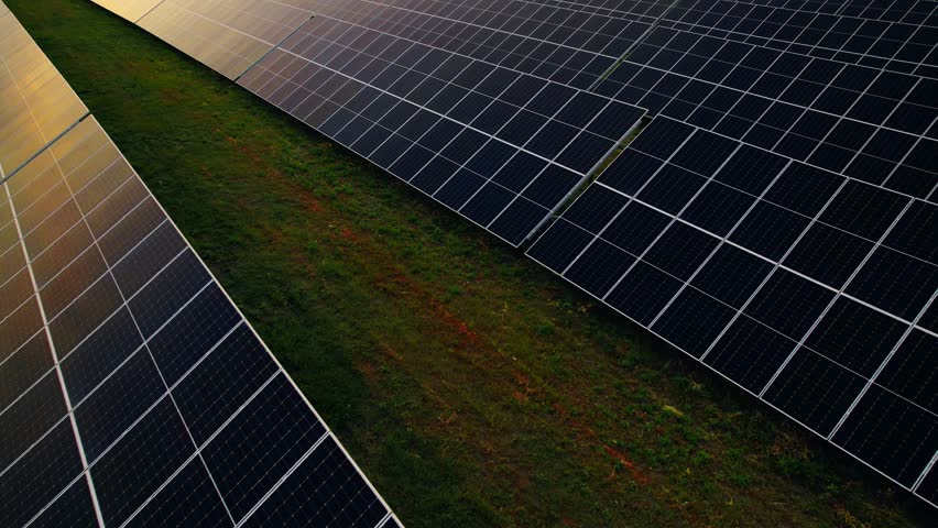 Aerial view of a solar farm generating solar energy.Solar panels park generating green energy electric at sunset.Green energy reduce carbon emissions and makes earth cleaner and more ecological.