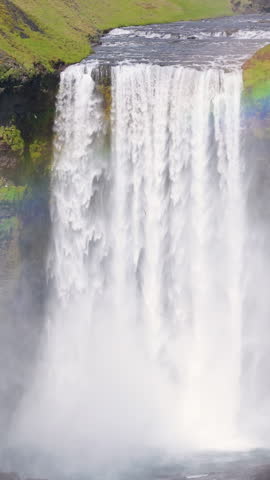 Aerial Skogafoss Waterfall in Iceland, complete with a rainbow view. Vertical