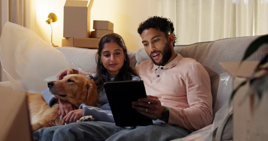 Couple, dog and tablet in new home to search for renovation idea, inspiration or moving service review. Man, woman and pet on sofa with technology for planning, relocation and mortgage payment plan