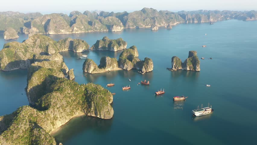 Multiple tourist boats are sailing in Ha Long Bay, Vietnam, near some characteristic rocky islands