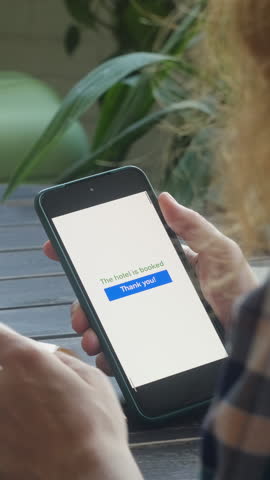 Vertical video. Online payment for last minute tour. Woman booking a hotel using bank card and smartphone
