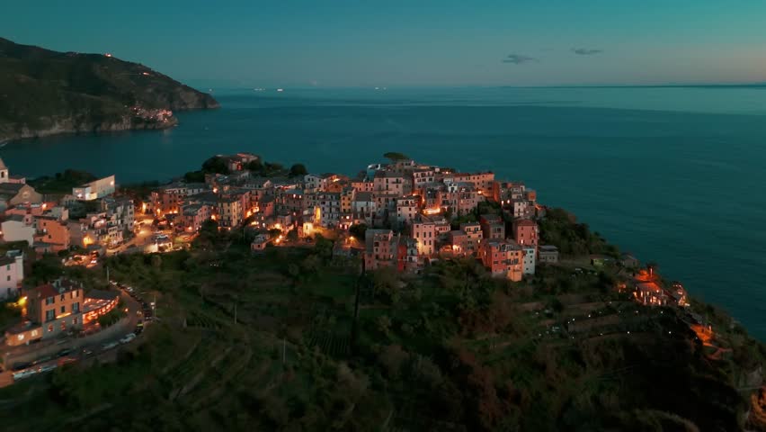 Aerial view of the picturesque resort town of Corniglia at night in the famous Cinque Terre, Liguria, Italy. Historic village with colorful buildings nestled between cliffs and the Ligurian Sea. 