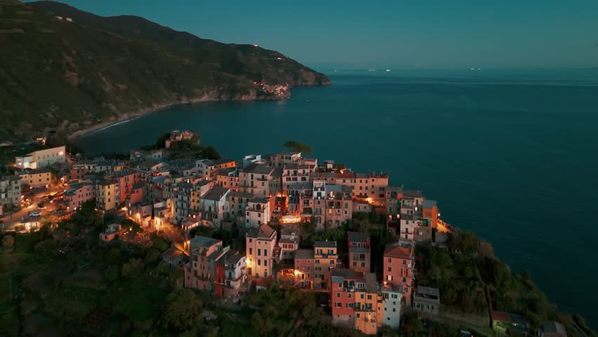 Aerial view of the picturesque resort town of Corniglia at night in the famous Cinque Terre, Liguria, Italy. Historic village with colorful buildings nestled between cliffs and the Ligurian Sea. 