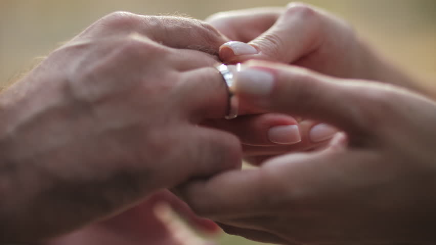 Woman putting ring on man finger