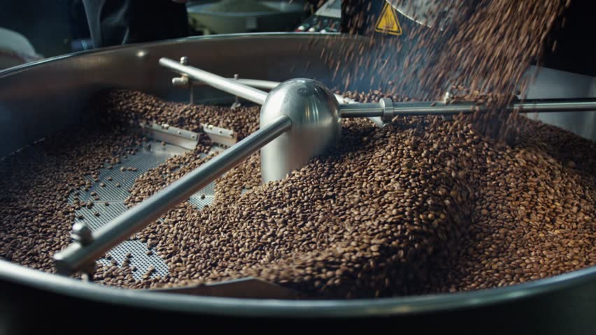 Freshly roasted coffee beans cooling and mixing in professional roasting equipment, revealing intense aroma and key stages of precision coffee manufacturing