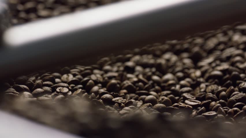 Roasted coffee beans cascading in slow motion, revealing rich brown texture and aromatic details of carefully roasted agricultural crop against neutral background