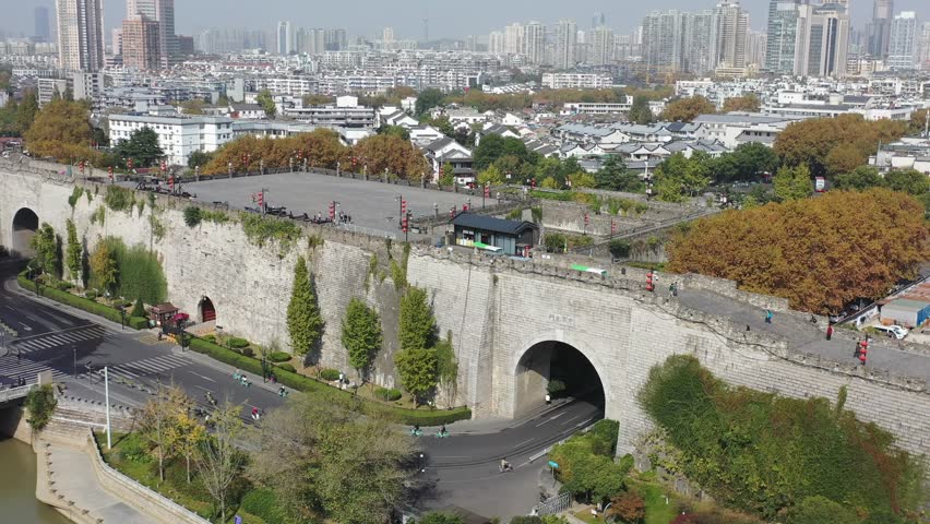 Aerial perspectives reveal the historic Nanjing Ancient City Gate surrounded by modern buildings and lush greenery. The vibrant streets are alive with activity, showcasing a blend of old and new.