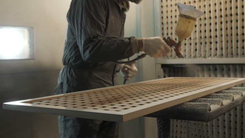Professional woodworker spraying protective coating on wooden panel, showcasing precise craftsmanship in well equipped workshop using specialized spray equipment