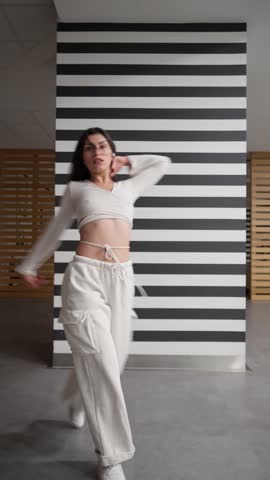 A happy young woman dances with a beautiful sense of rhythm and flow. Feeling the music, her body moves with fluid, energetic grace, showing the pure joy and freedom of expressive movement.