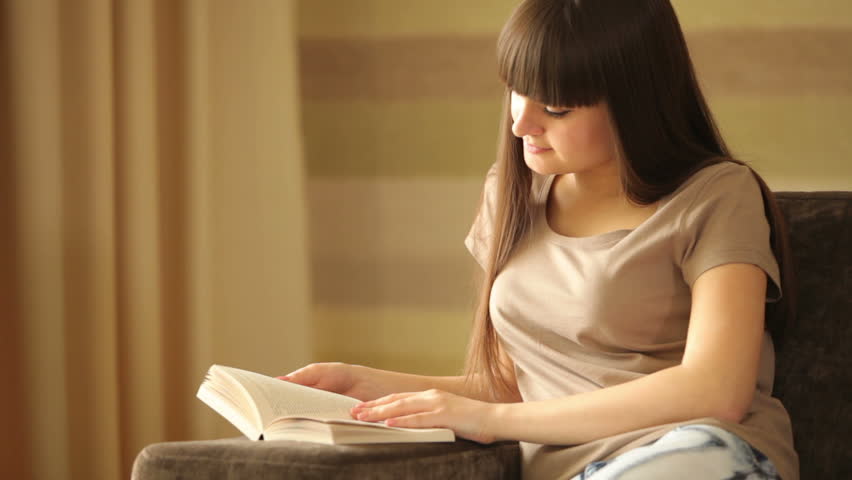 Cute girl reading and looking at camera with smile

