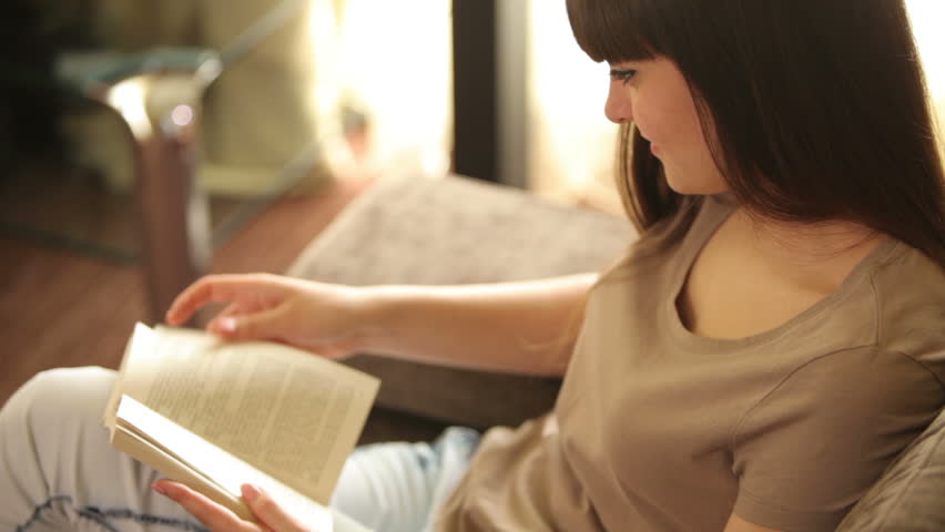 Girl holding a book and reading with smile

