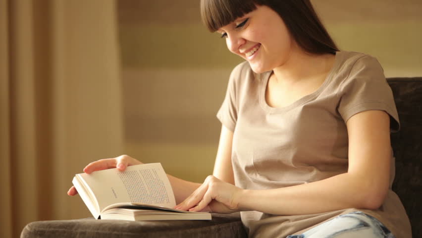 Cute girl reading a book and laughing
