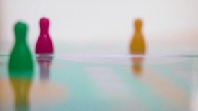 A white dice falls in front of green, pink and yellow pawns on a glossy board, shifting shallow focus from tokens to dice. The sequence emphasizes motion, chance and anticipation in tabletop gameplay. - Powered by Shutterstock - Get 15% off with code: PIKWIZARD15