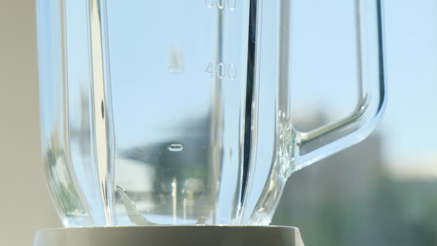 Close-up of oat flakes falling into a glass blender jar to be ground into flour for low-calorie oat bread. Healthy oats serve as a base ingredient for diet baking and clean vegetarian nutrition.