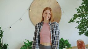 Smiling woman in a casual outfit poses playfully in a cozy indoor space with plants and soft lighting - Powered by Shutterstock - Get 15% off with code: PIKWIZARD15