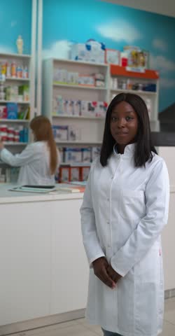 Young female pharmacist smiling and posing in a pharmacy, showcasing professionalism and expertise