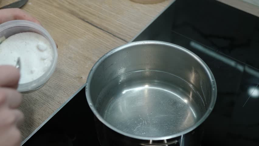 Demonstration showcases in detail how to effectively mix salt into water using a stainless steel pot, while focusing on the essential technique of dissolving for various culinary applications