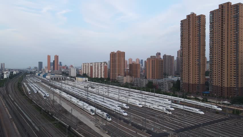 Stunning aerial perspective over Wuhan high speed train station highlights an array of modern trains lined up against the backdrop of the urban skyline.