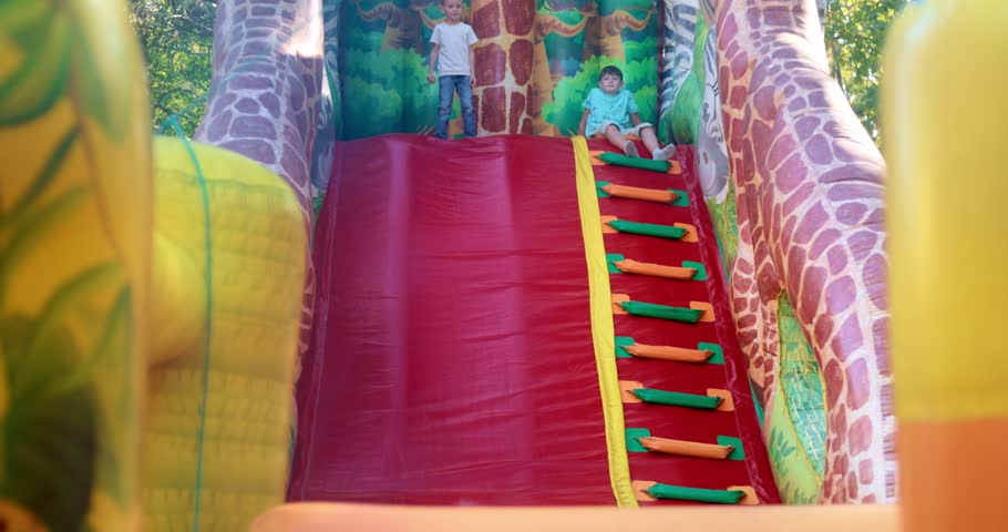 Children Playing on Inflatable Slide at Outdoor Playground