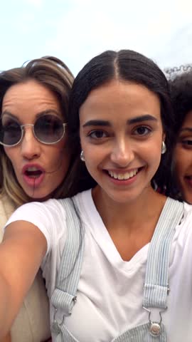 Diverse group of young women sharing genuine moments of joy, capturing friendship through candid selfie during summer outdoor adventure