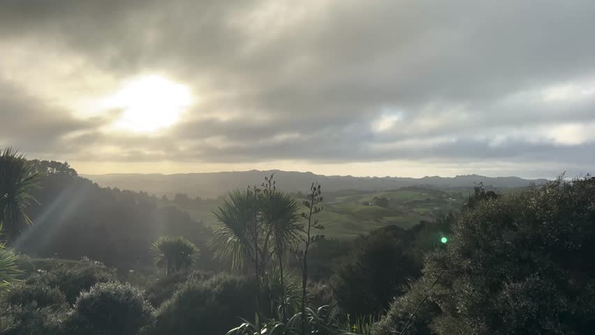 Sunrise view in East Tamaki, Auckland, New Zealand. Green hills and trees under blue sky.