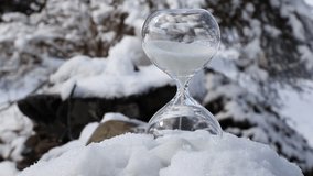 Conceptual image of switching to winter time or fall back, end of daylight saving time. Selective focus on hourglass with sand falling in the winter in snowy nature. - Powered by Shutterstock - Get 15% off with code: PIKWIZARD15