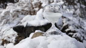 Conceptual image of switching to winter time or fall back, end of daylight saving time. Selective focus on hourglass with sand falling in the winter in snowy nature. - Powered by Shutterstock - Get 15% off with code: PIKWIZARD15