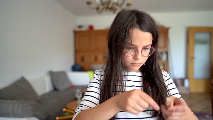 Child engaged in handicrafts indoors, dressed in glasses and striped sweater. Concept: creative growth, educational play, self-expression, cozy environment.