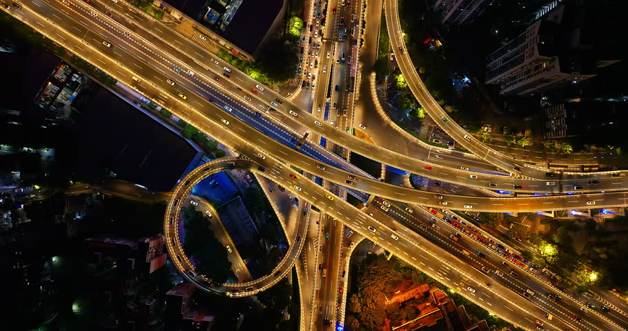 Aerial shot of an illuminated urban highway interchange with busy traffic flow in a modern city at night