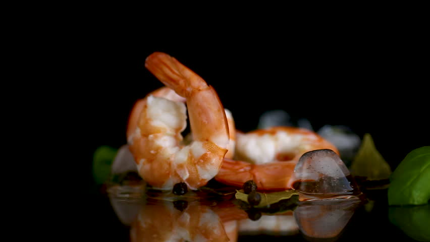 Boiled shrimp with ice and spices on a black background