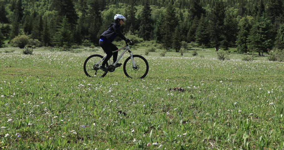Riding mountain bike in the beautiful flowering grassland and forest mountain trail