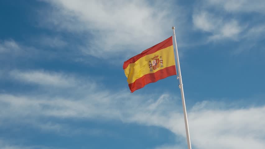 Spanish flag waving gracefully against a bright blue sky. A powerful symbol of national pride, unity, and heritage, capturing the essence of Spains cultural identity