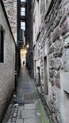 Young female tourist walk in a close street which is subject of horror stories during the black plague in Edinburgh.