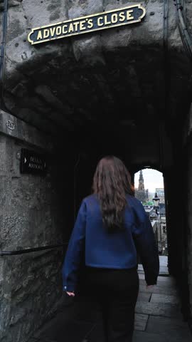 Young female tourist walk in a close street which is subject of horror stories during the black plague in Edinburgh.