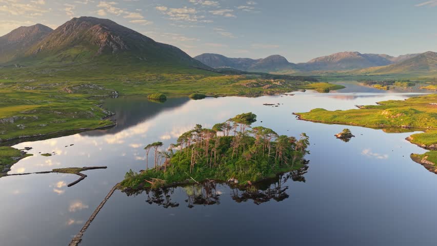 Aerial sunset view of Twelve Pines Island in Connemara National Park, Galway, Ireland. Fly over green island, Derryclare Lough lake and mountains in the background in Connemara NP
