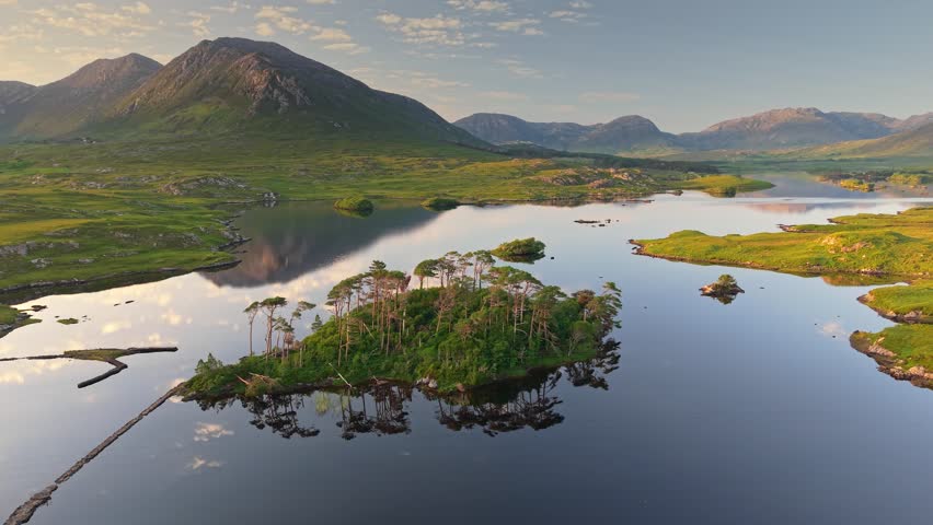 Aerial sunset view of Twelve Pines Island in Connemara National Park, Galway, Ireland. Fly over green island, Derryclare Lough lake and mountains in the background in Connemara NP