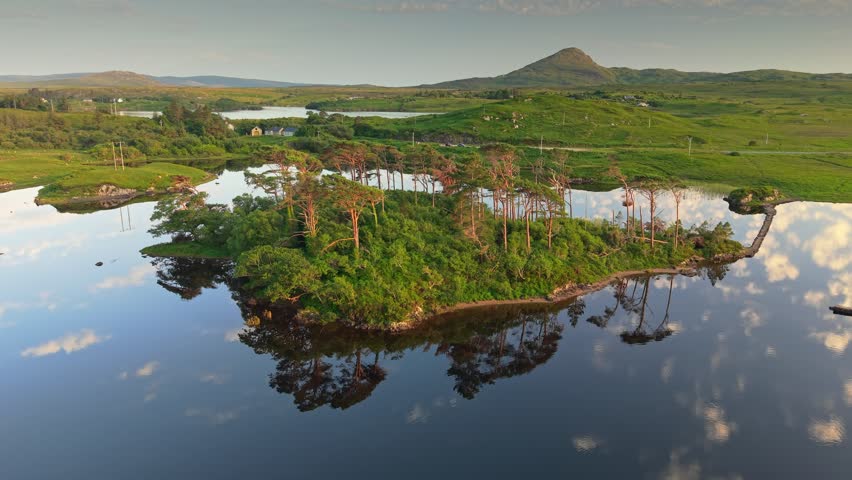 Aerial breathtaking landscapes of Connemara National Park in Ireland, Galway during golden hour. Fly over green island, Derryclare Lough lake and mountains