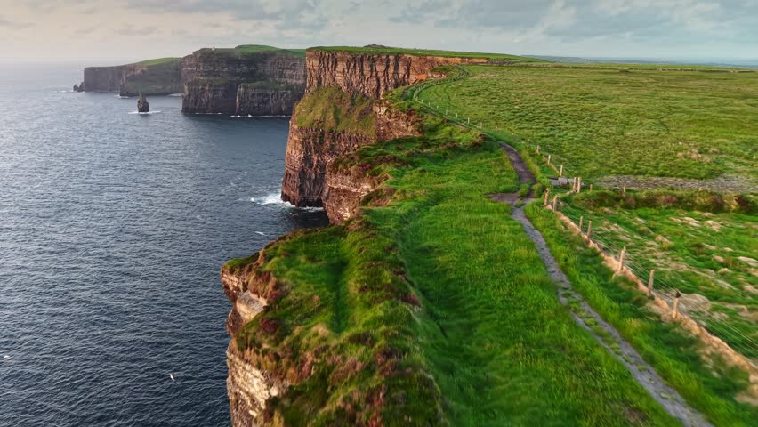 Flying over path near the edge of Cliff of Moher - one of the most popular tourist destinations in Ireland. Aerial breathtaking cliffs of Moher in Ireland, County Clare