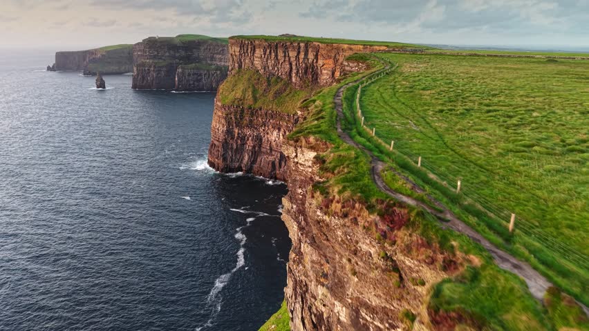Flying over path near the edge of Cliff of Moher - one of the most popular tourist destinations in Ireland. Aerial breathtaking cliffs of Moher in Ireland, County Clare