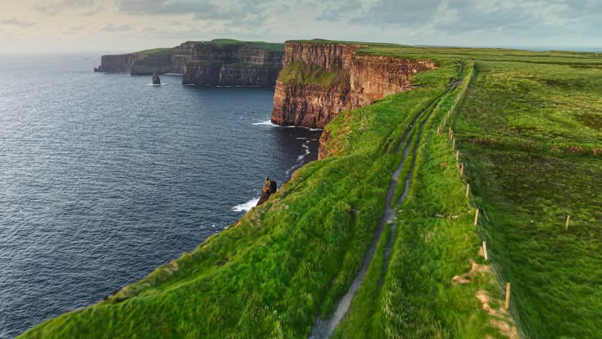 Aerial coastal views along the Cliffs of Moher in Ireland featuring cliffs and Atlantic Ocean during sunset. flying along the edge in one of the most beautiful places in Ireland - Cliffs of Moher