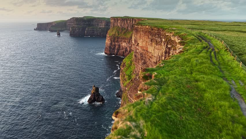 Aerial coastal views along the Cliffs of Moher in Ireland featuring cliffs and Atlantic Ocean during sunset. flying along the edge in one of the most beautiful places in Ireland - Cliffs of Moher