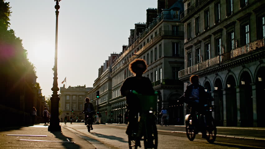 Architecture and bicycle traffic on the streets of Paris at sunset. Silhouettes of people walking through the capital of France.