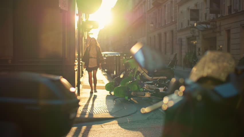 Woman tourist walks through romantic streets of Paris at sunset. Beautiful architecture of historic streets of the capital of France, girl on a trip through a beautiful European city.